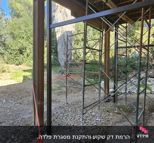 פיגומים מתכתיים מתחת למבנה עץ בגינה